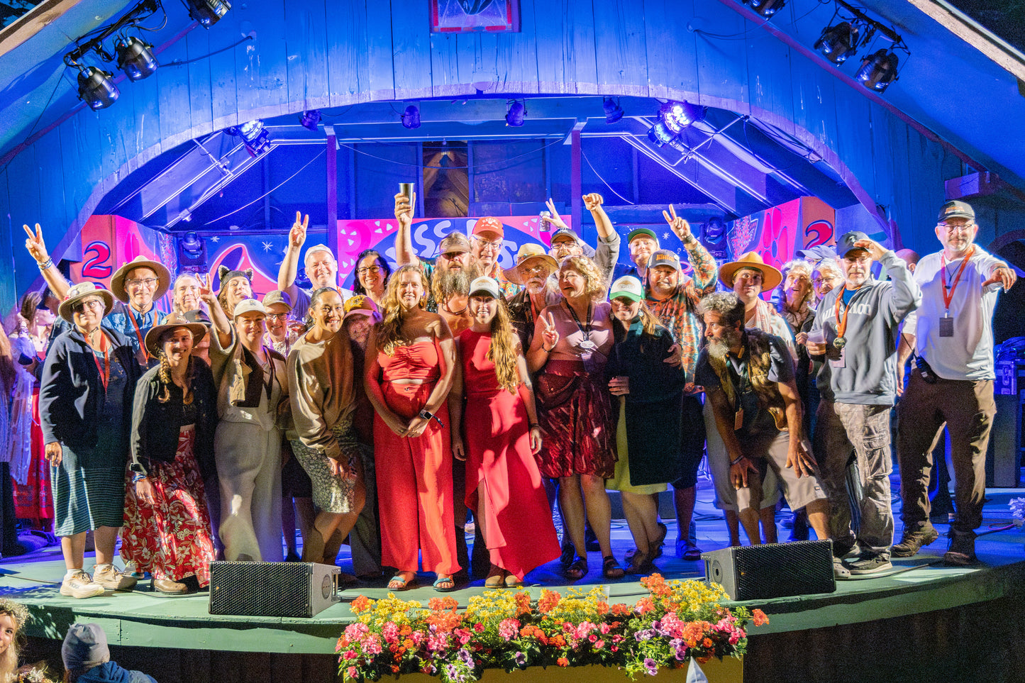 Group of people on a stage with colorful backdrop and floral decorations.