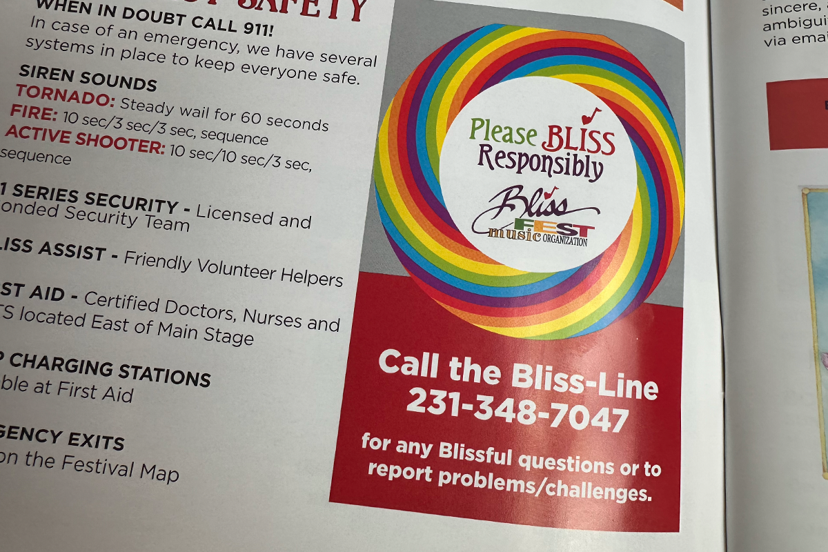 Safety information card with Bliss music festival contact details and rainbow logo.