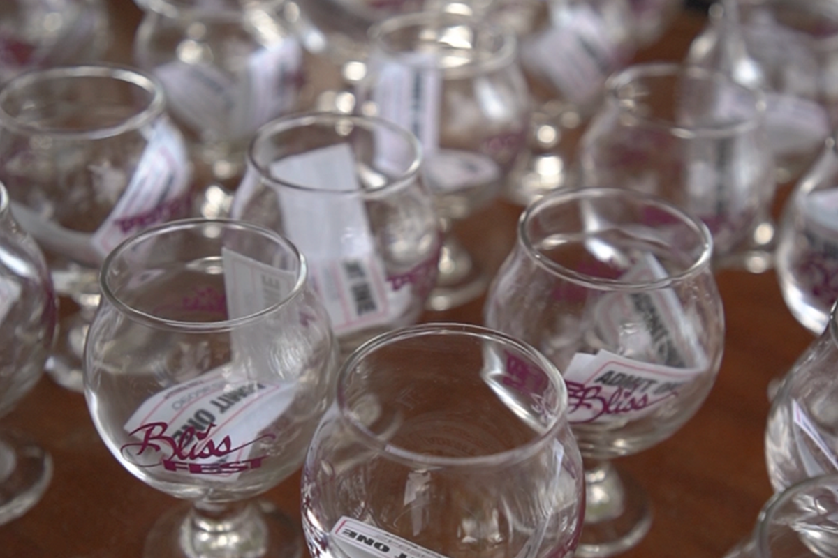 Collection of clear glass goblets with 'Bliss' labels on a wooden surface